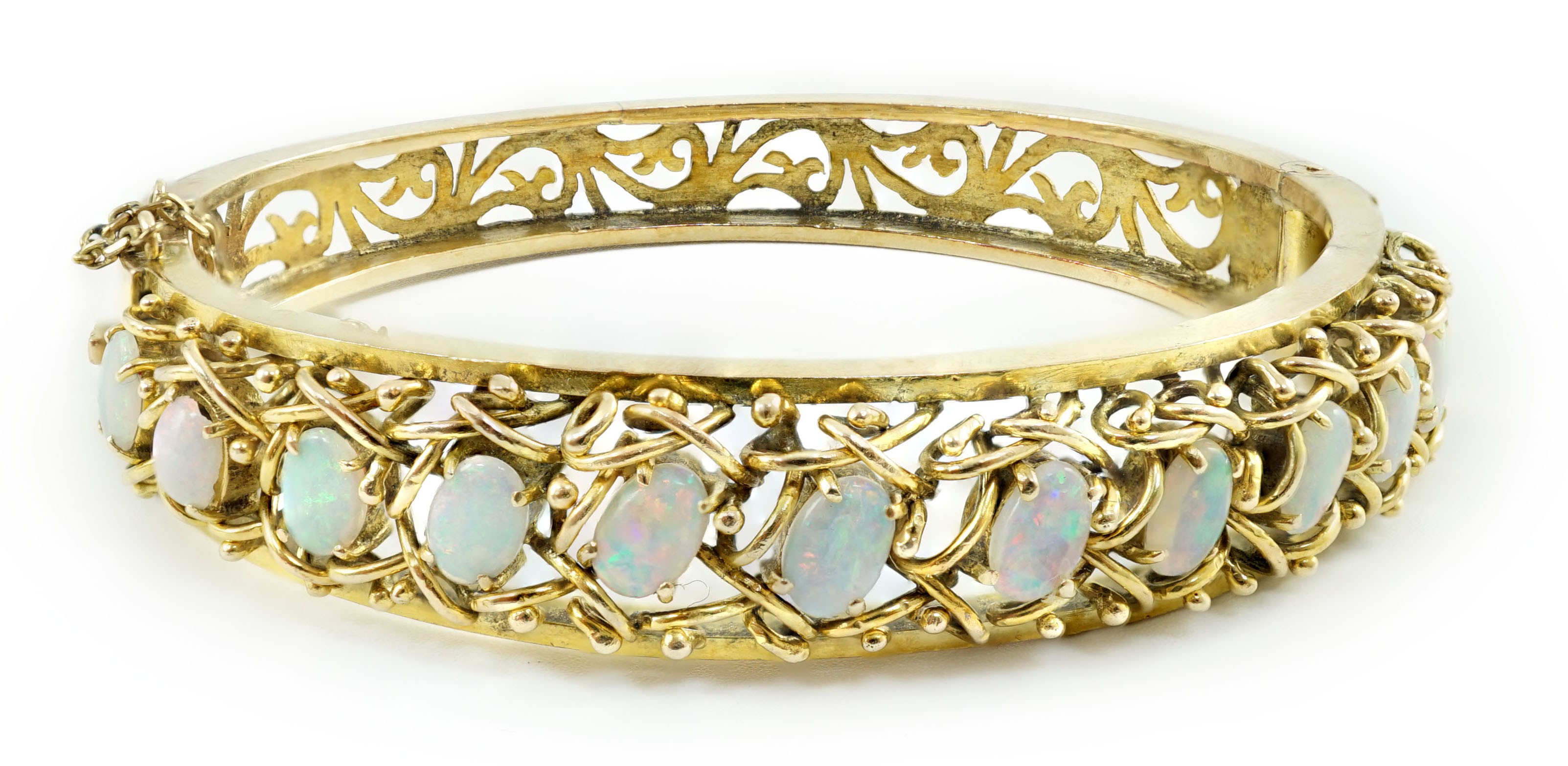 A pierced gold and twelve stone oval white opal set hinged bangle